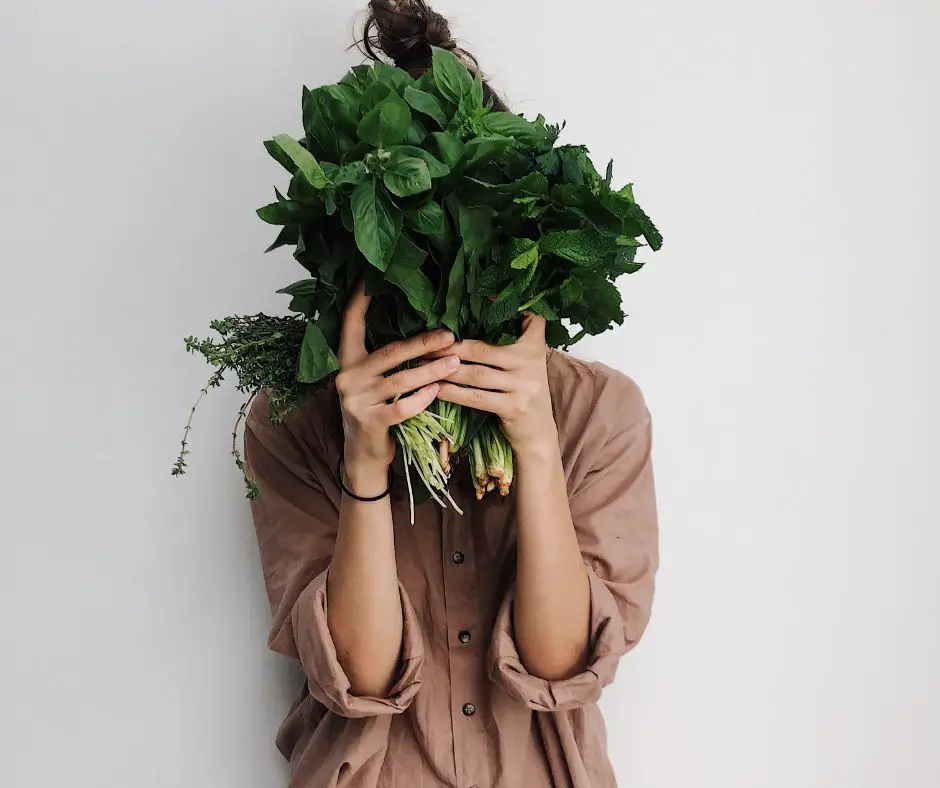 A girl is holding a bunch of basil.