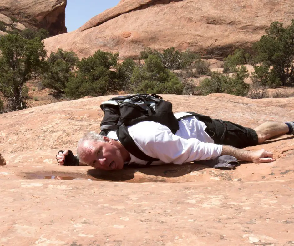 A man is drinking water from a small hole.